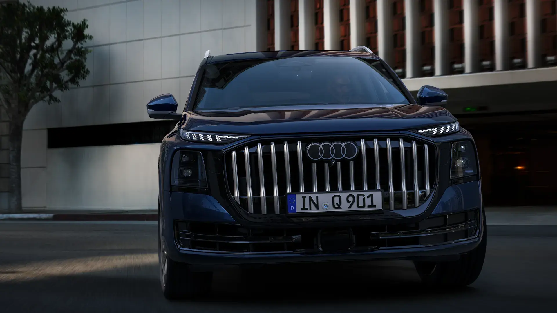 Mørkeblå Audi SUV set forfra i bymiljø med fokus på den store, lodrette kølergrill og LED-forlygter.