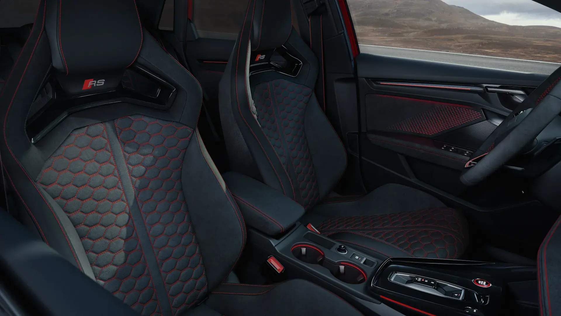 Interiør af en Audi RS 3 med sportslige forsæder i sort alcantara med rød syning og RS-logo.
